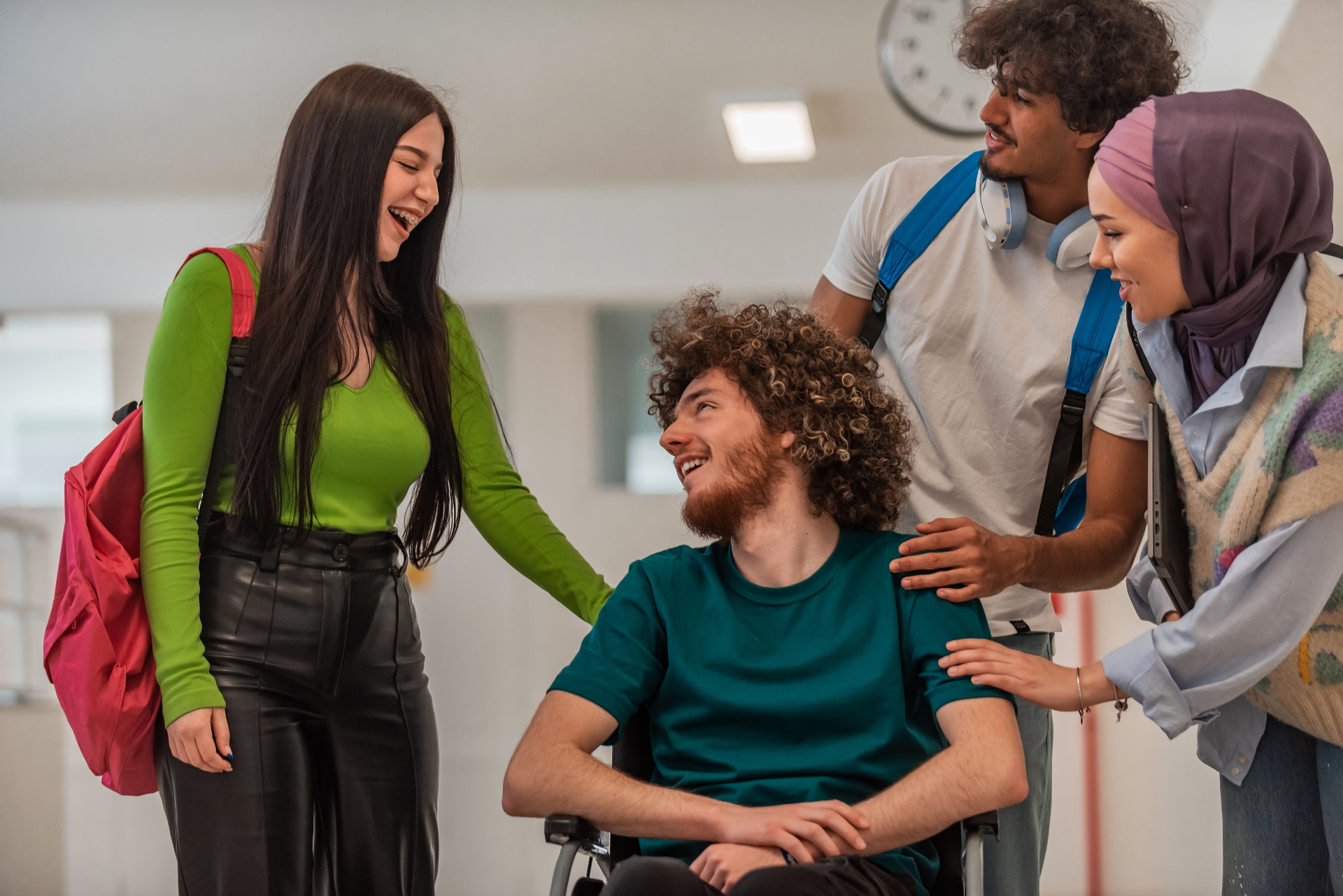 A group of young people including a person in a wheelchair, smiling and connecting together
